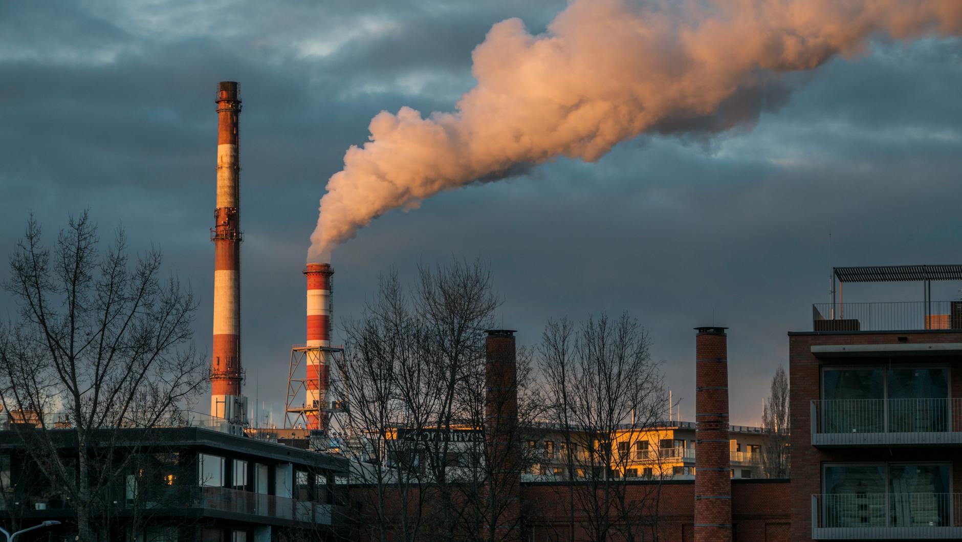 Chimneys of an industrial plant releasing smoke against a dramatic sky in Wrocław.